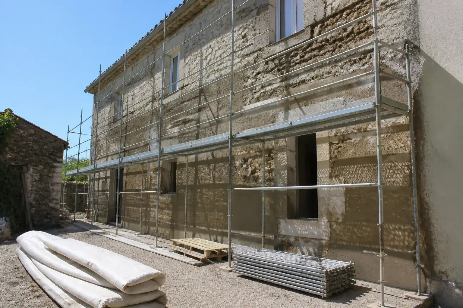 Façade en cours de rénovation extérieure avec échafaudage tubulaire le long d’un mur en pierre
