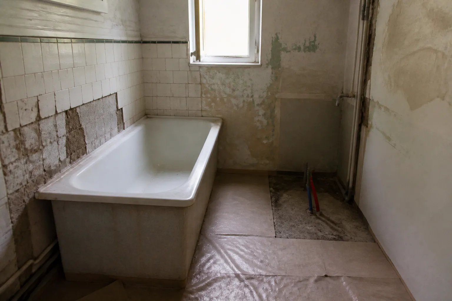 Salle de bain ancienne en cours de rénovation, ancien carrelage partiellement déposé